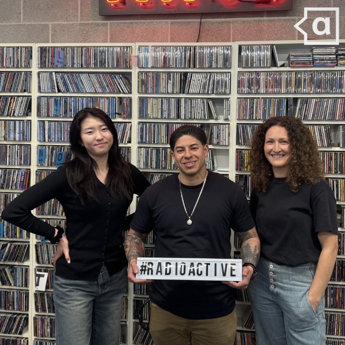 Estelle, Diego, and Crystal standing in front of a CD wall.