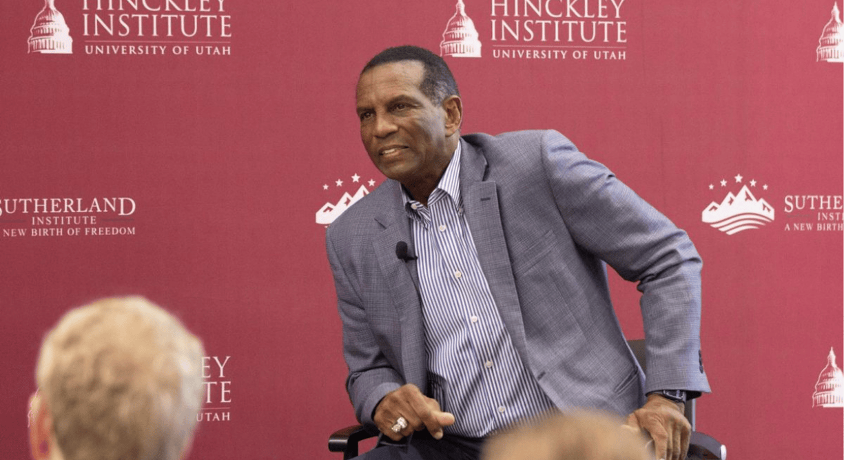 Burgess Owens talking in front of a red background